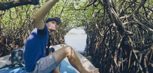 Cropped image of a traveler exploring Madu River mangrove tunnels by boat