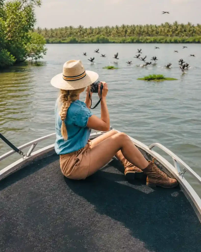 Woman using binoculars to watch birds during a Madu River safari