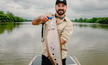 Happy fisherman showing a big fish caught on the Madu River