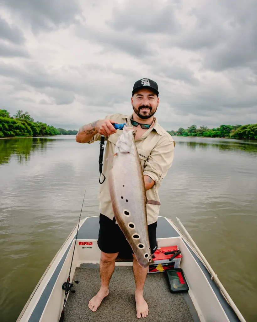 Happy fisherman showing a big fish caught on the Madu River