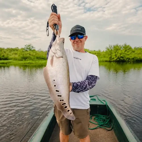 Traveler holding a freshly caught fish during a Madu River fishing trip