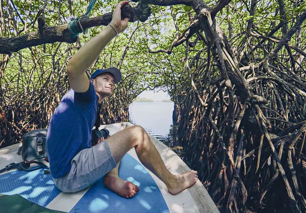 Visitor exploring Madu River mangrove tunnels by boat