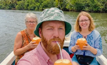 Tourists drinking fresh king coconut during a Madu River boat safari