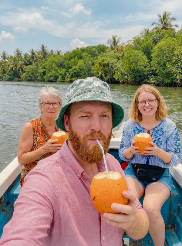 Tourists drinking fresh king coconut during a Madu River boat safari