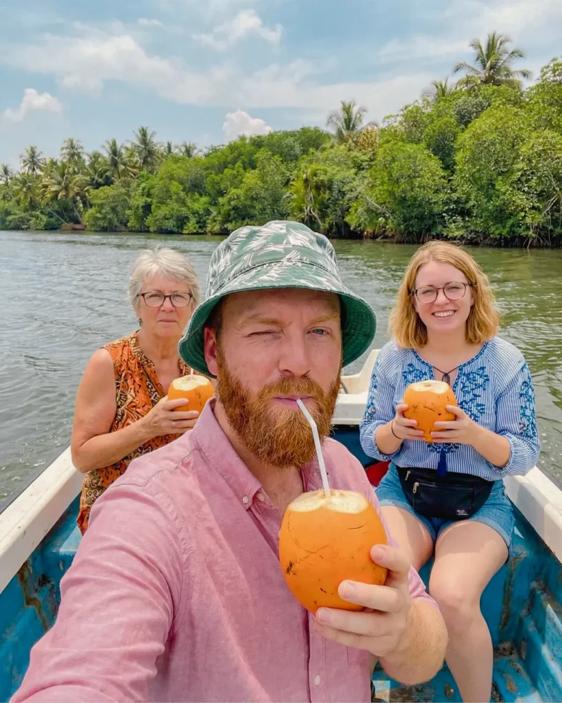 Tourists drinking fresh king coconut during a Madu River boat safari