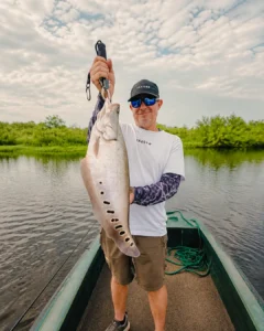 Traveler holding a freshly caught fish during a Madu River fishing trip
