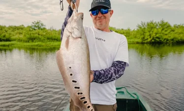 Traveler holding a freshly caught fish during a Madu River fishing trip