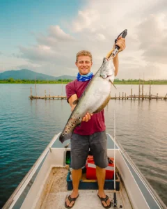 Angler proudly showing a large fish caught during river fishing on the Madu River