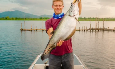 Angler proudly showing a large fish caught during river fishing on the Madu River