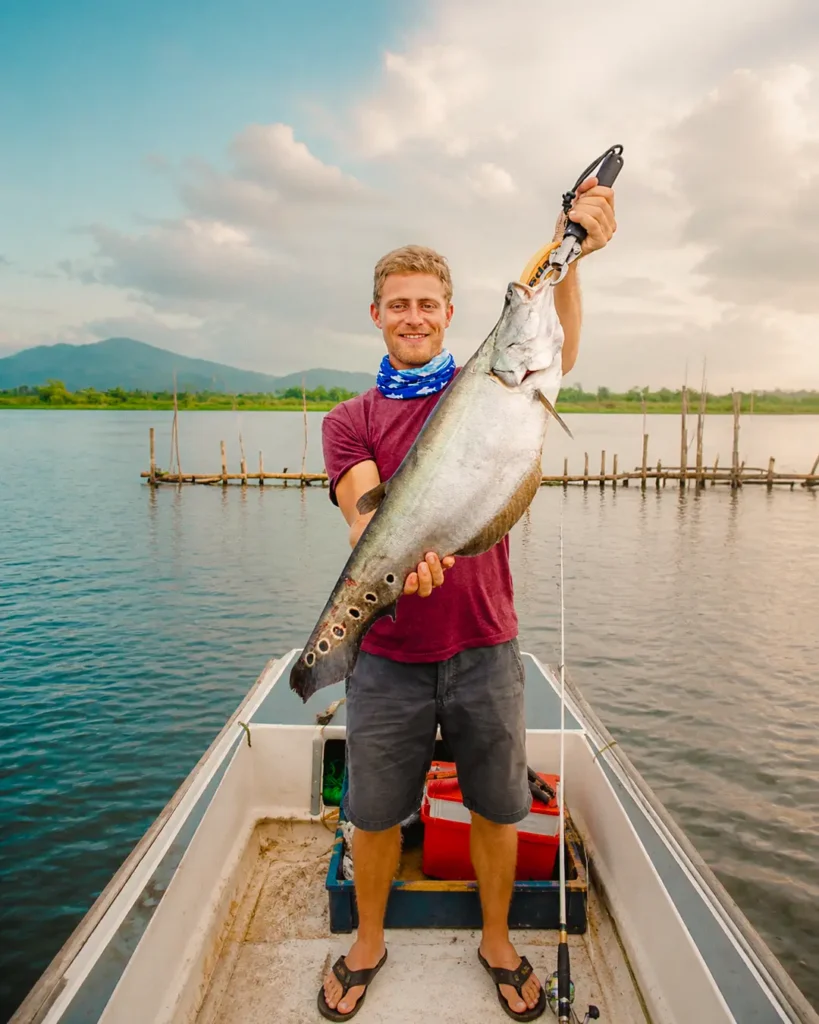 Angler proudly showing a large fish caught during river fishing on the Madu River