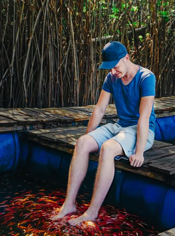 Visitor enjoying natural fish therapy during a Madu River boat safari
