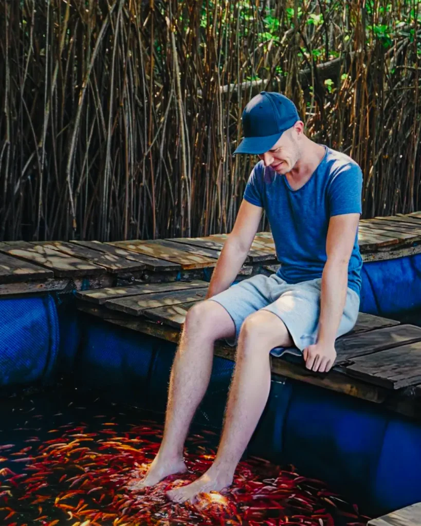 Visitor enjoying natural fish therapy during a Madu River boat safari